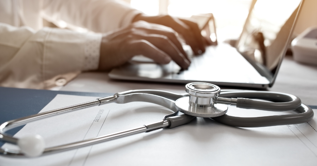 doctor typing on computer with stethoscope in the foreground